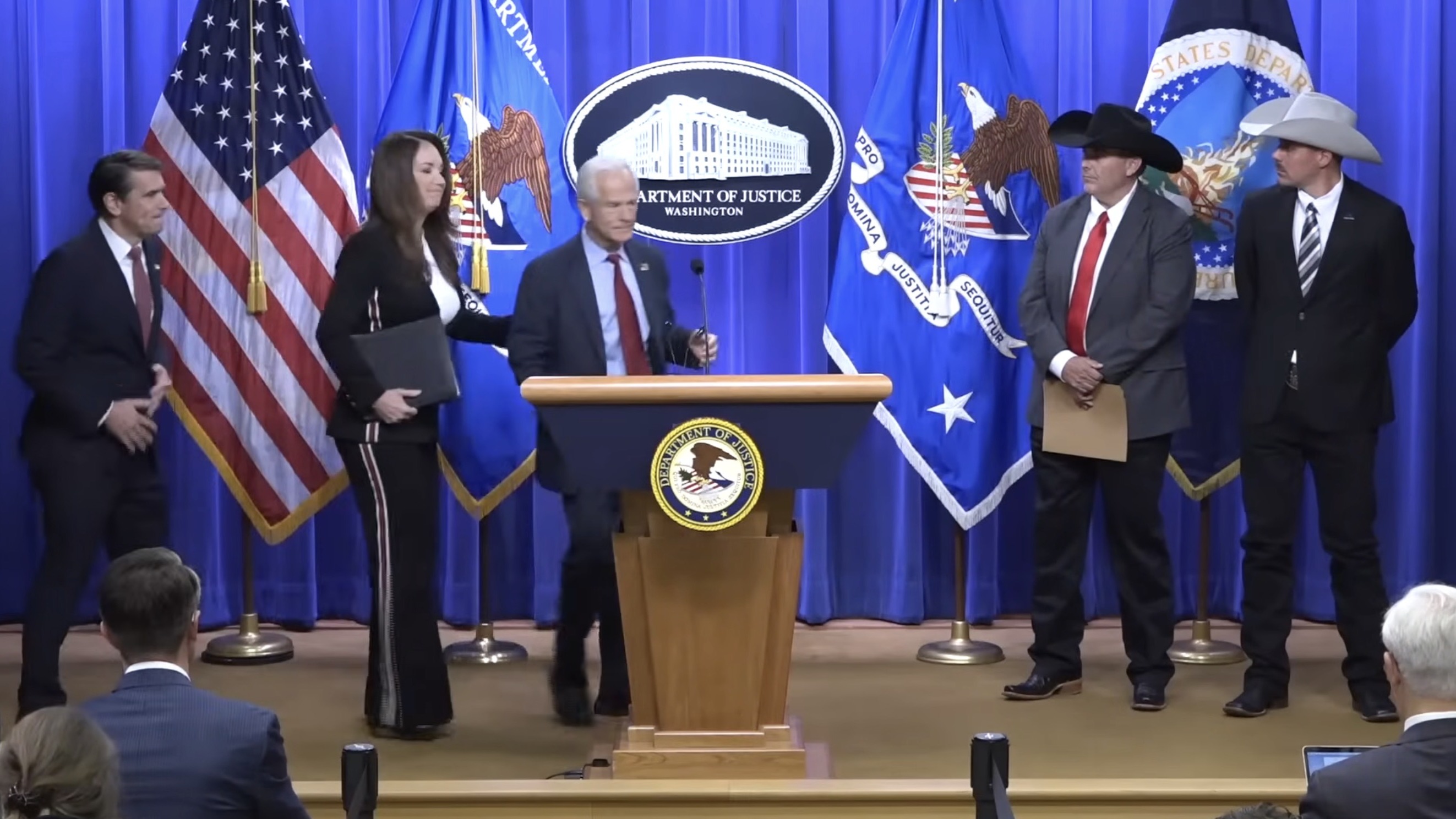 Acting AG Todd Blanche, Secretary Brooke Rollins, and Trade Director Peter Navarro at the DOJ press conference, May 4, 2026.